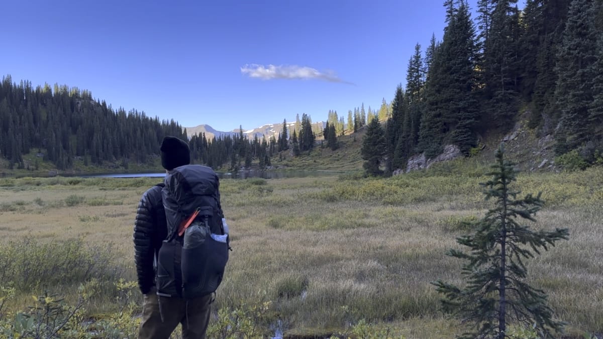 Backpacker in mountain valley with evergreen forest view of Geneva Lake.
