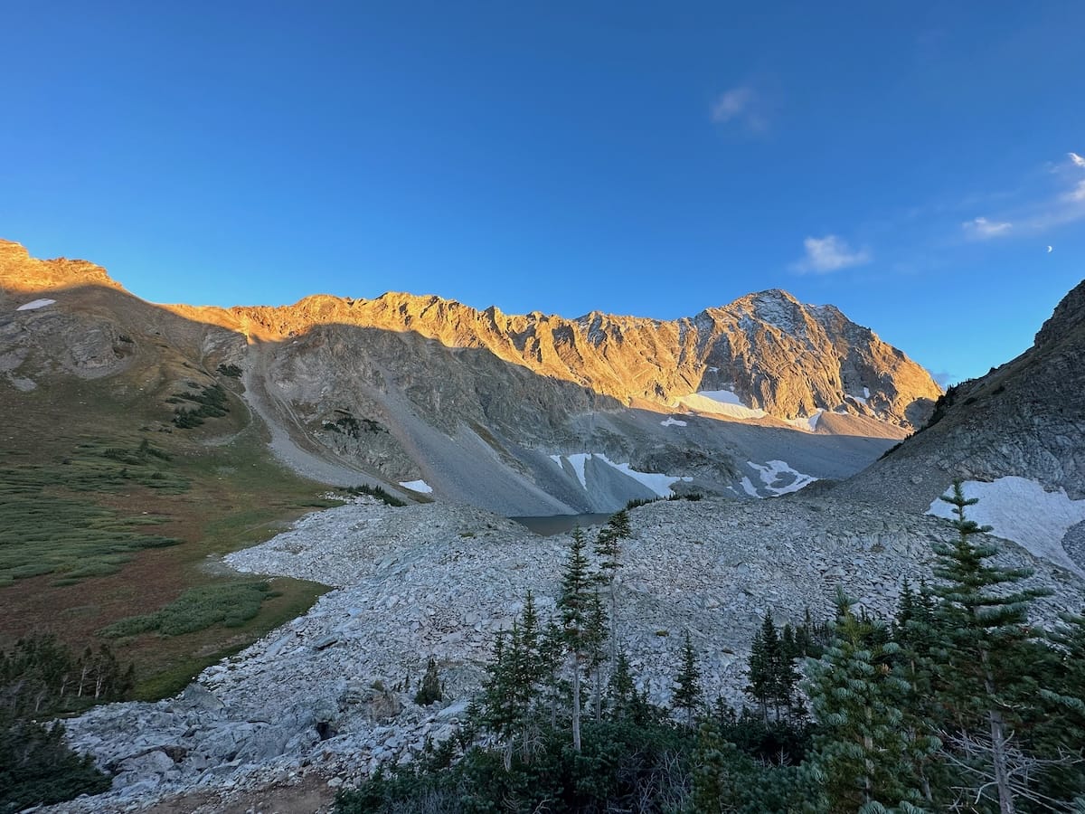 Mountain sunrise view of Capitol Peak with rocky landscape.