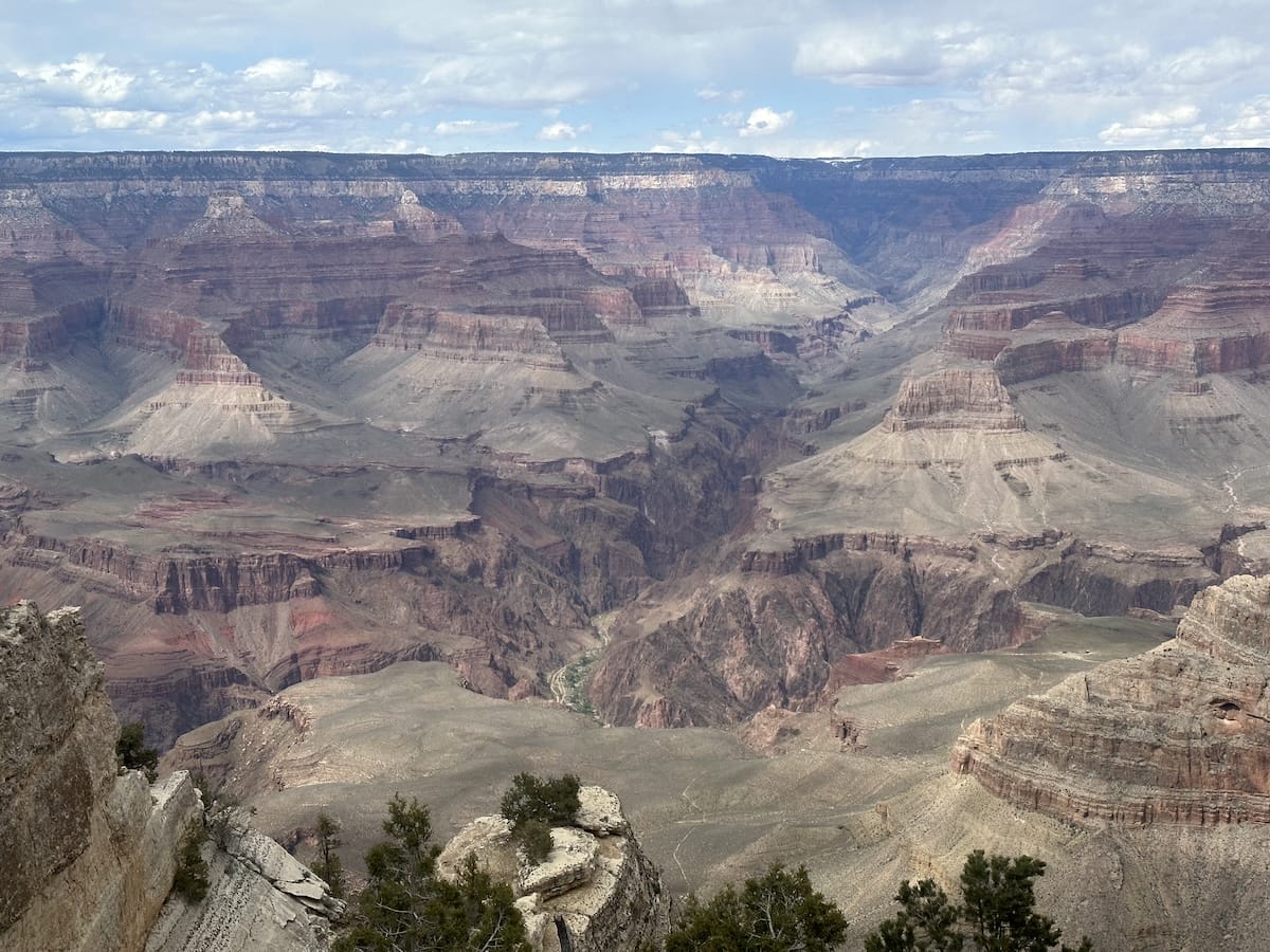 grand-canyon-scenic-view-canyon-landscape Panoramic view of the Grand Canyon with layered rock formations and a partly cloudy sky.