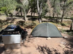 Campsite at Phantom Ranch in Grand Canyon National Park with a green Tarptent Rainbow, picnic table, and bear box.