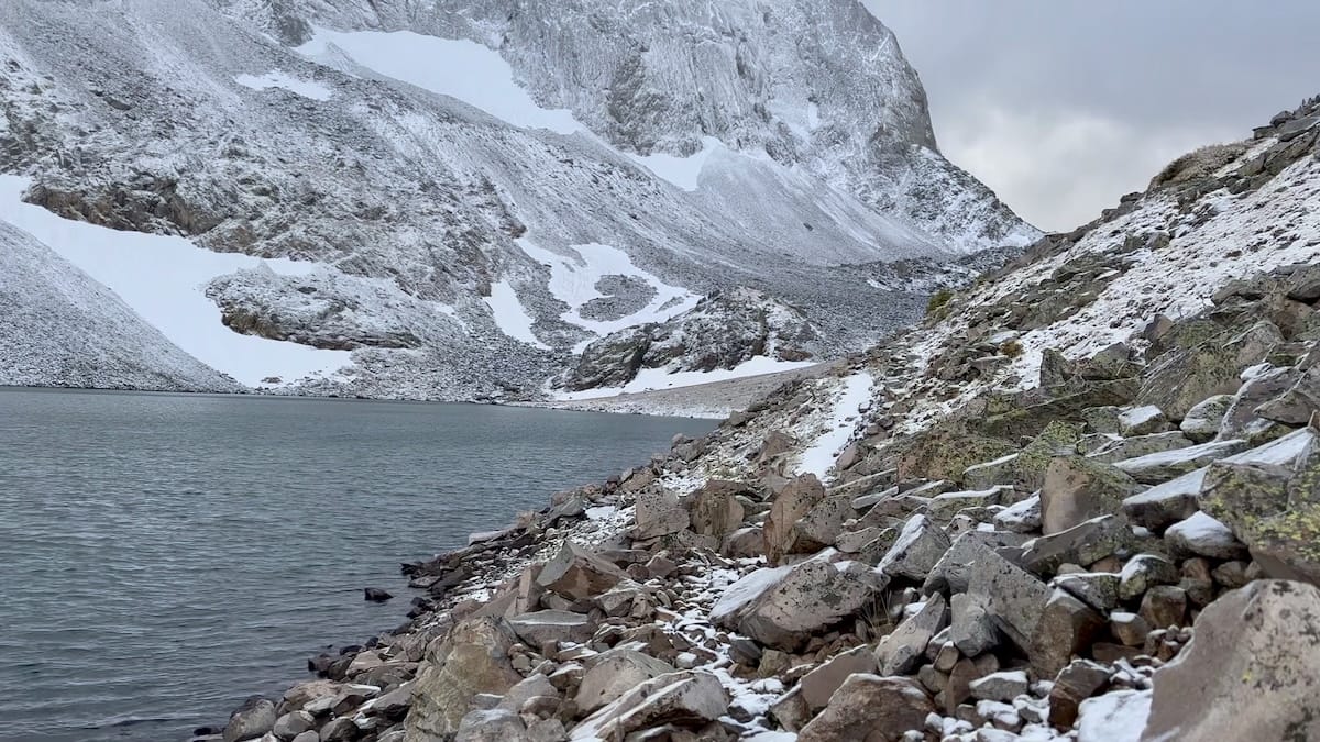 Snowy lake with mountain rocks on Capitol Peak Trail.