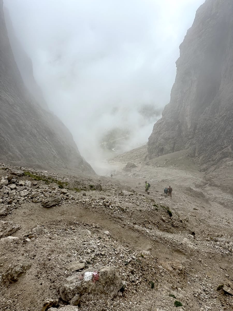 Hikers navigating a rocky ravine with mist on the Alta Via 2.