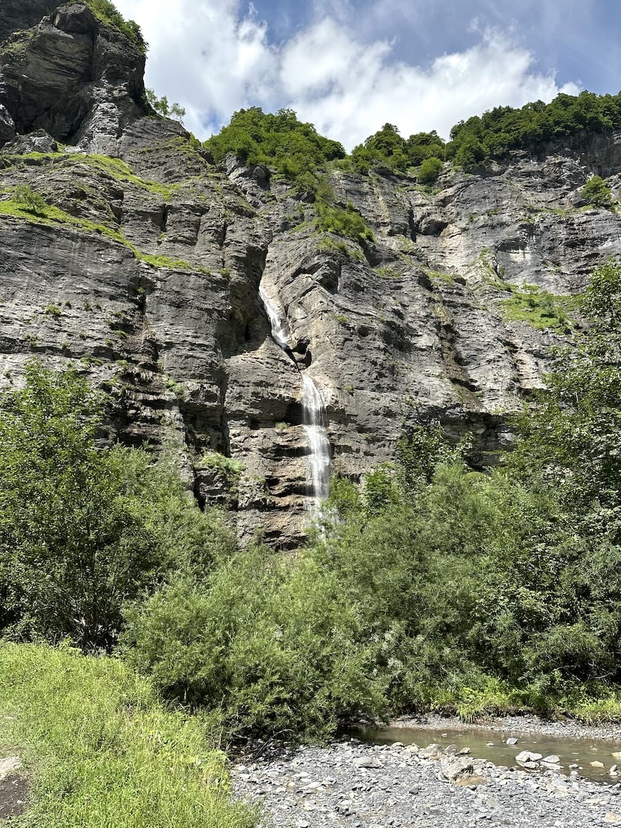 Waterfall cascading down rocky cliff into riverbed in Cirque du Fer-à-Cheval.