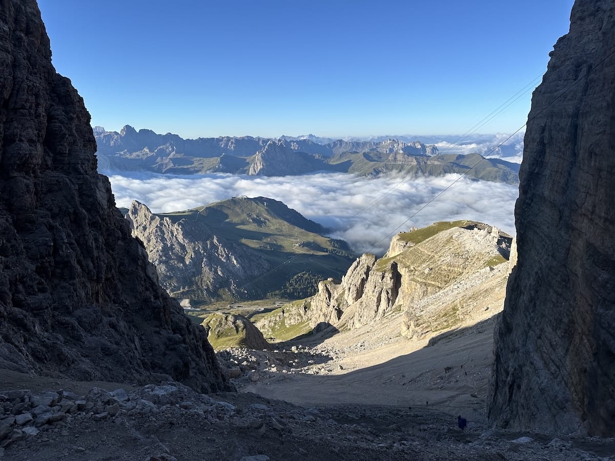 View from Forcella Pordoi with clouds, valley, and rock faces in the Dolomites.
