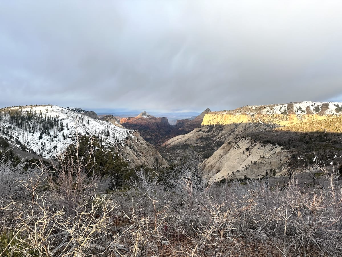 Canyon view along the Zion Traverse with snow-covered areas and arid shrubs.