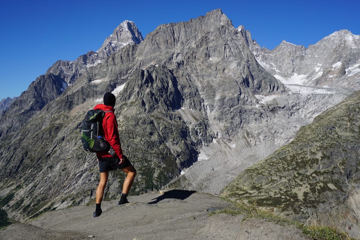osprey-exos-48-mount-blanc Hiker wearing Osprey Exos backpack and red rain jacket at a look out of Mont Blanc.