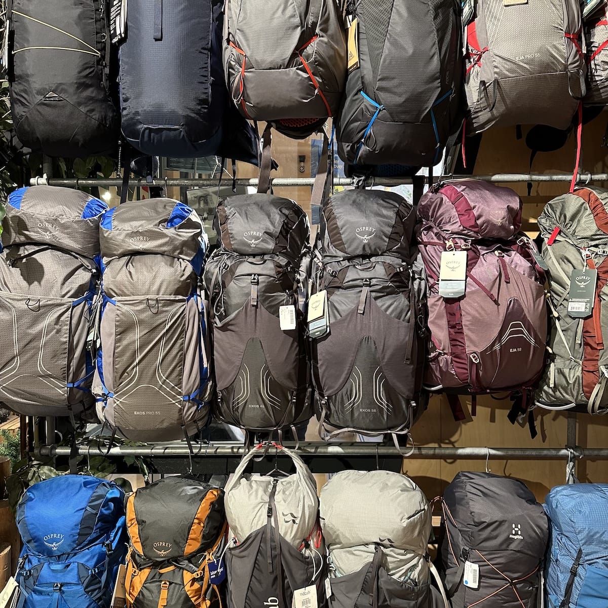 A store display of Osprey backpacks on a wall.