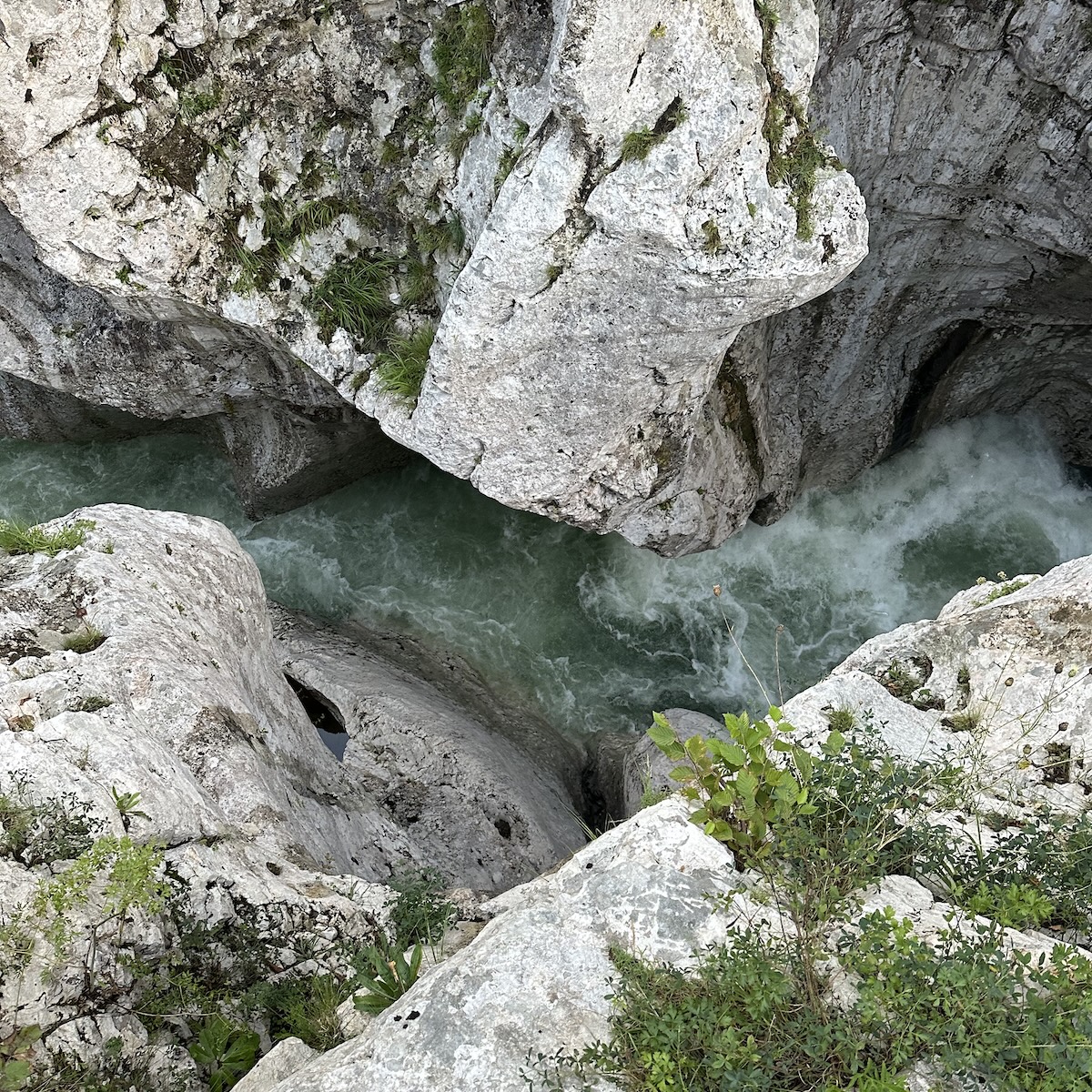 The Soča River winding through tight limestone curves with rushing water below