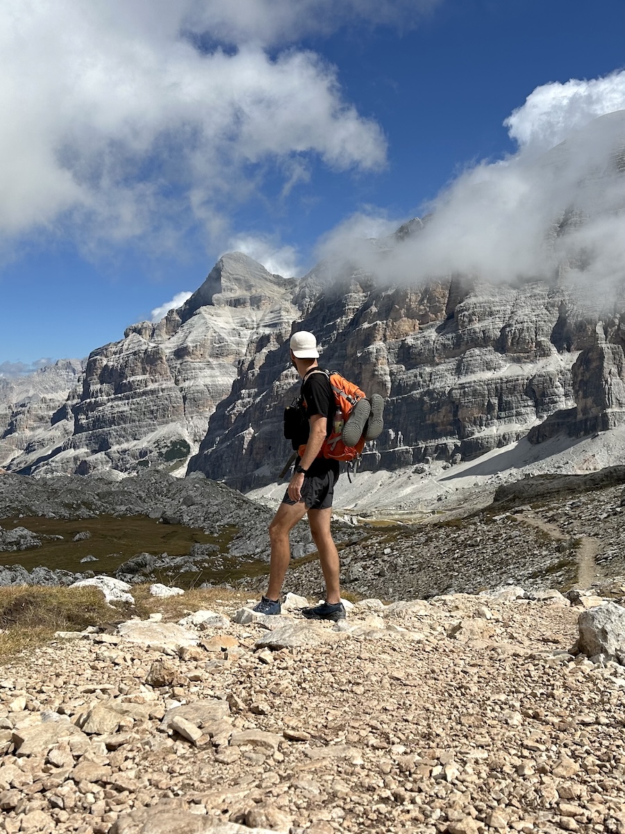 Hiker with backpack overlooking Dolomite cliffs