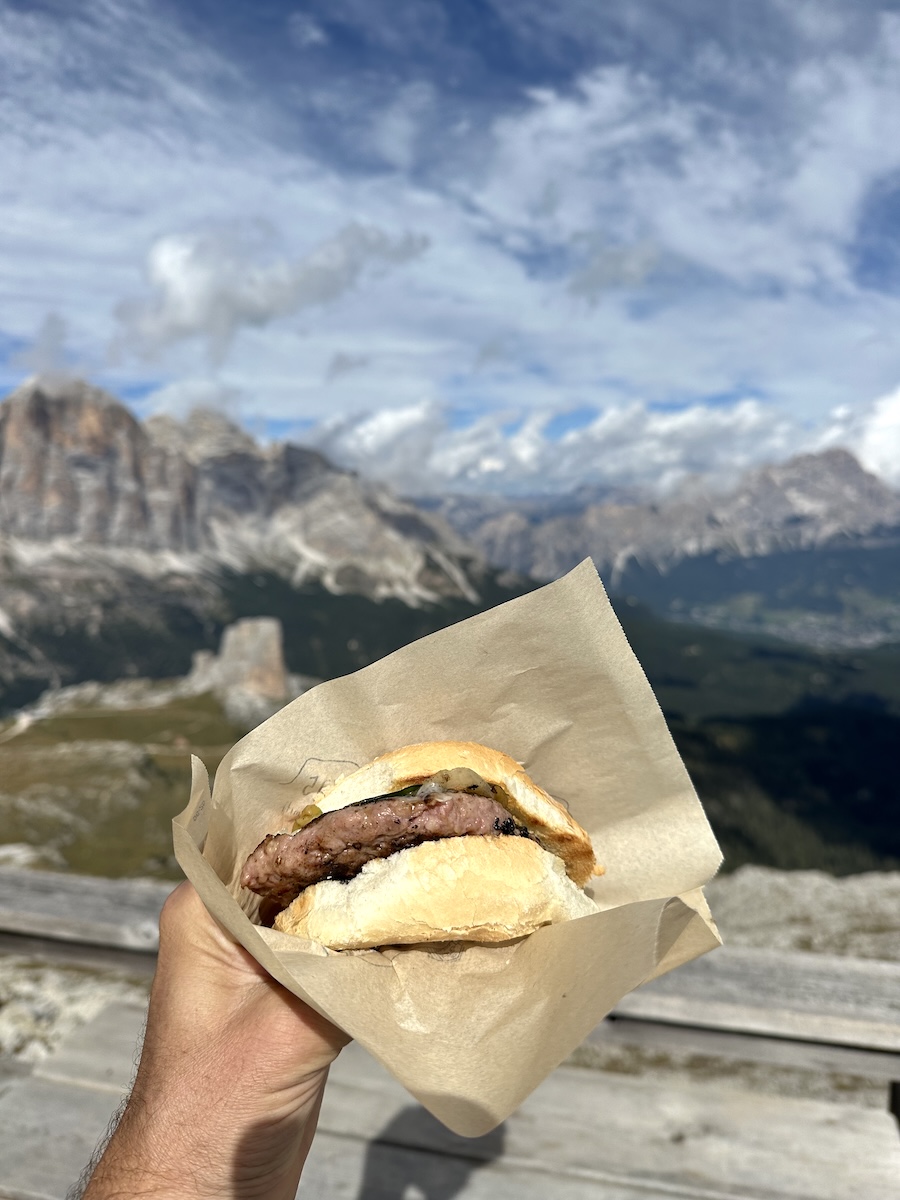 Hand holding burger with Dolomite view