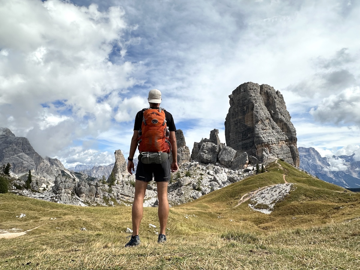 Backpacker facing Cinque Torri rock towers