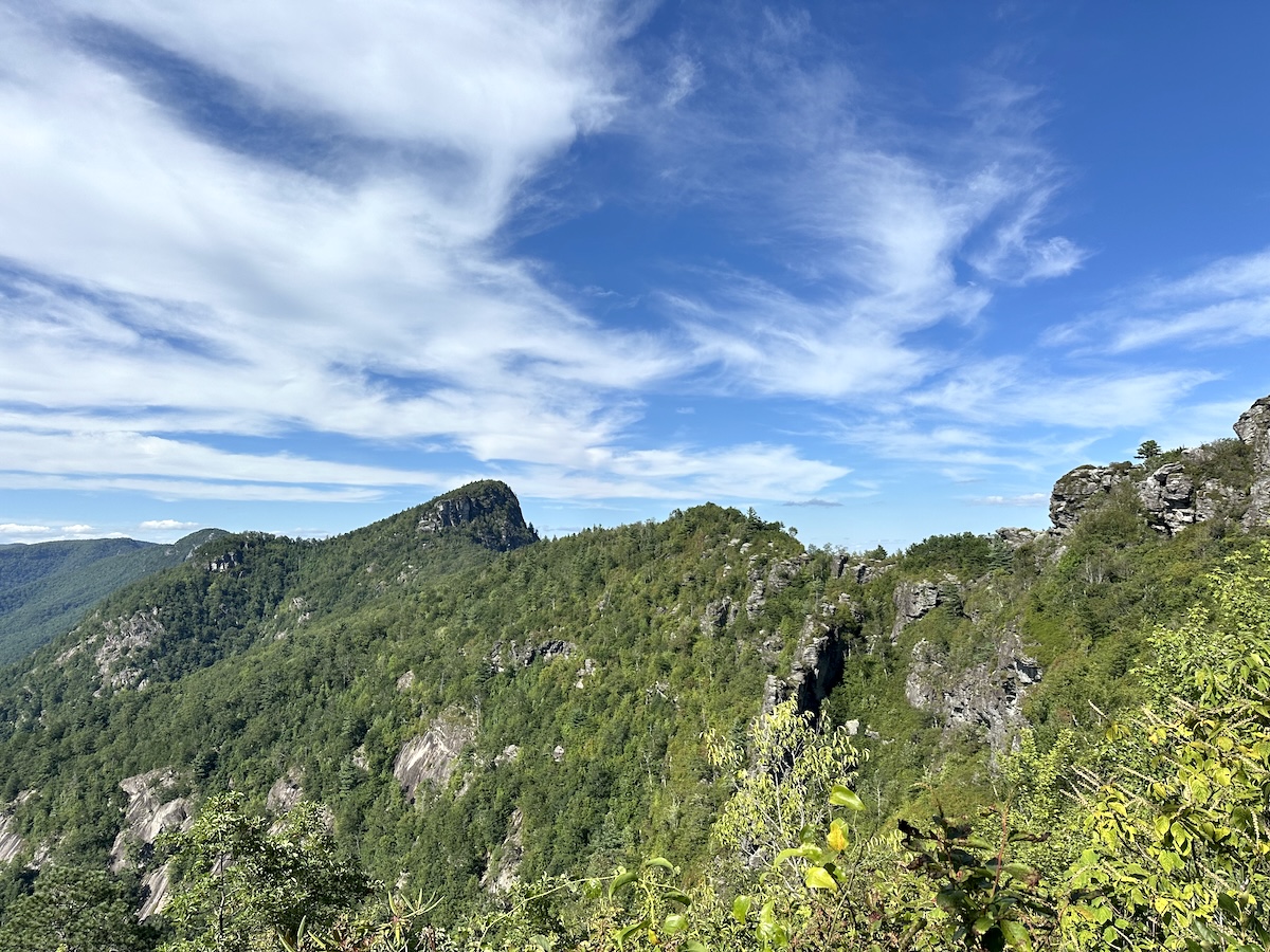 Jagged gorge rim with rocky pinnacles and high clouds drifting overhead.