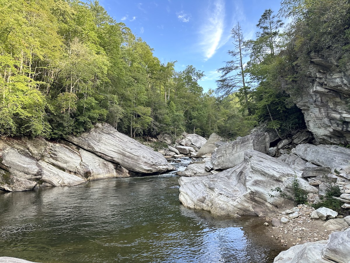 Clear pool on the Linville River bordered by smooth gray bedrock slabs and forest.