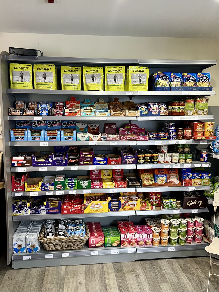 Well-stocked food and snack shelves at Beinglas Campsite shop on the West Highland Way including freeze-dried meals and energy bars.