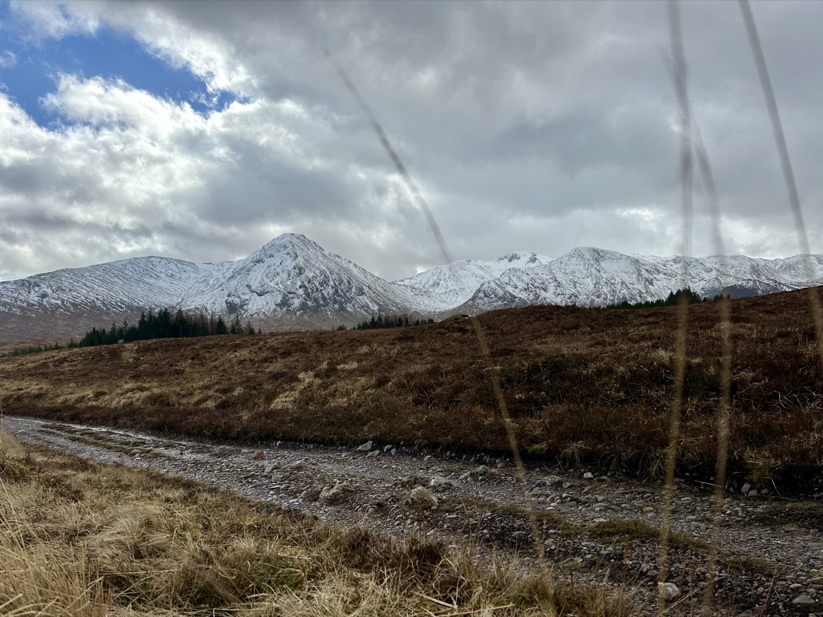 Gravel track across Black Mount with heavily snow-covered peaks on the West Highland Way