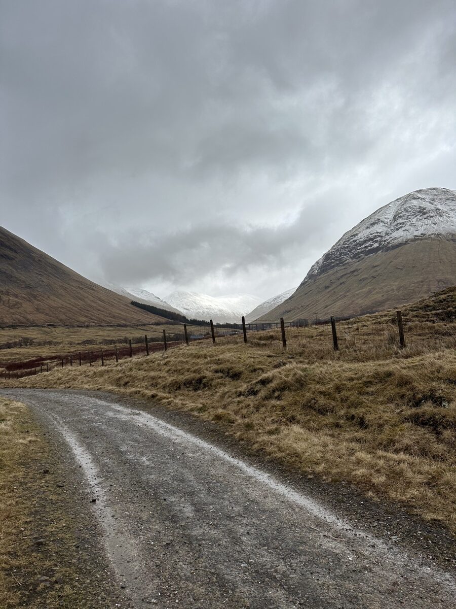Wet gravel track descending through Glen Falloch valley toward Crianlarich on the West Highland Way