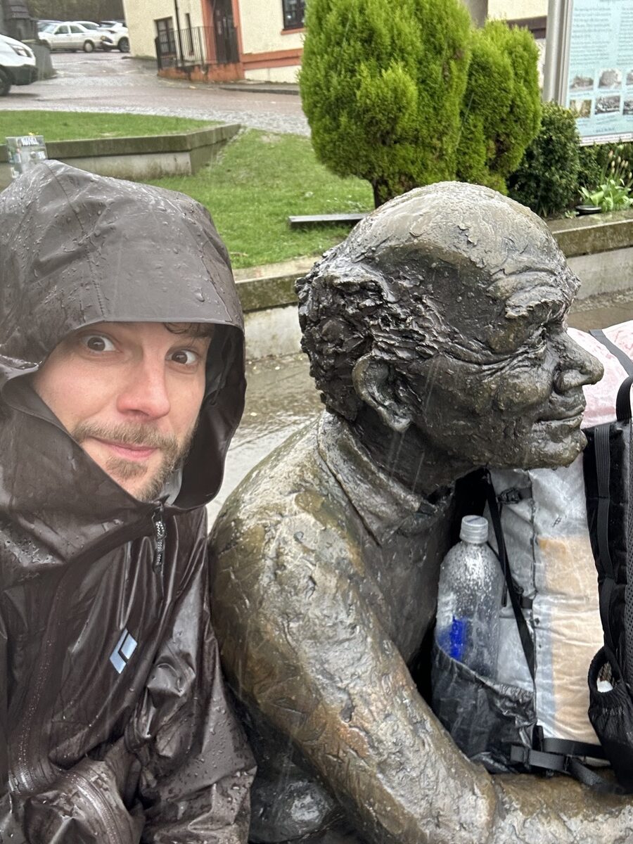 Hiker selfie with the West Highland Way finish statue in Fort William in the rain