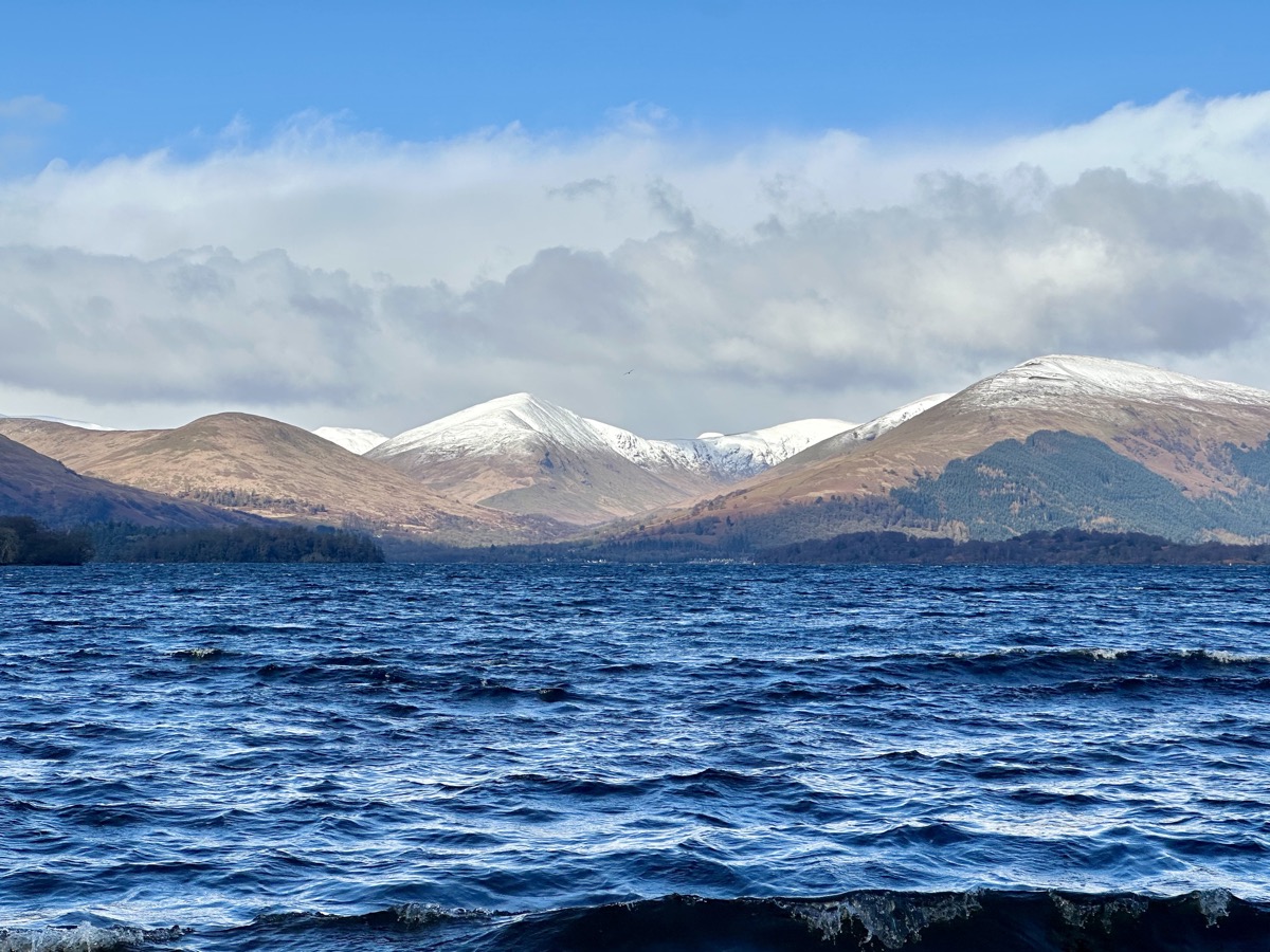 Panoramic view across Loch Lomond toward snow-covered mountains from the West Highland Way