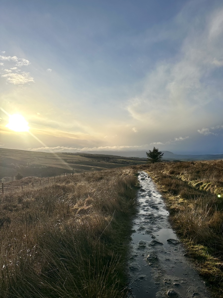Muddy waterlogged trail across open moorland at sunset on the West Highland Way