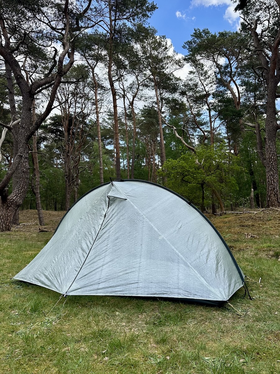 Tarptent Rainbow Li DCF Side Angle Pine Forest Tarptent Rainbow Li DCF ultralight tent pitched on grass in a pine forest showing the full arch profile and side angle