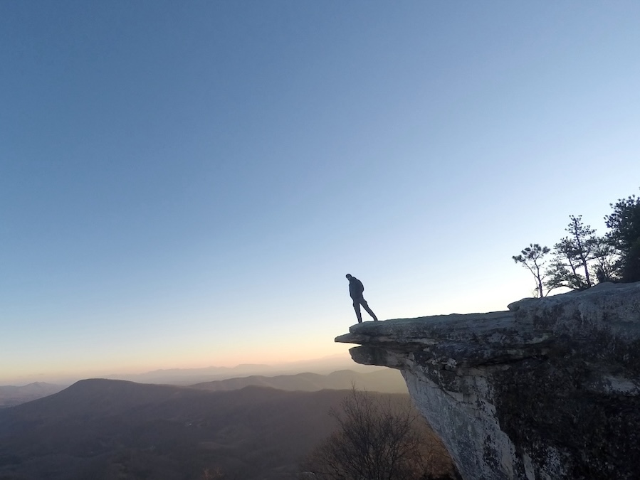 Hikeron the edge of Mcafee Knob during the morning sunrise
