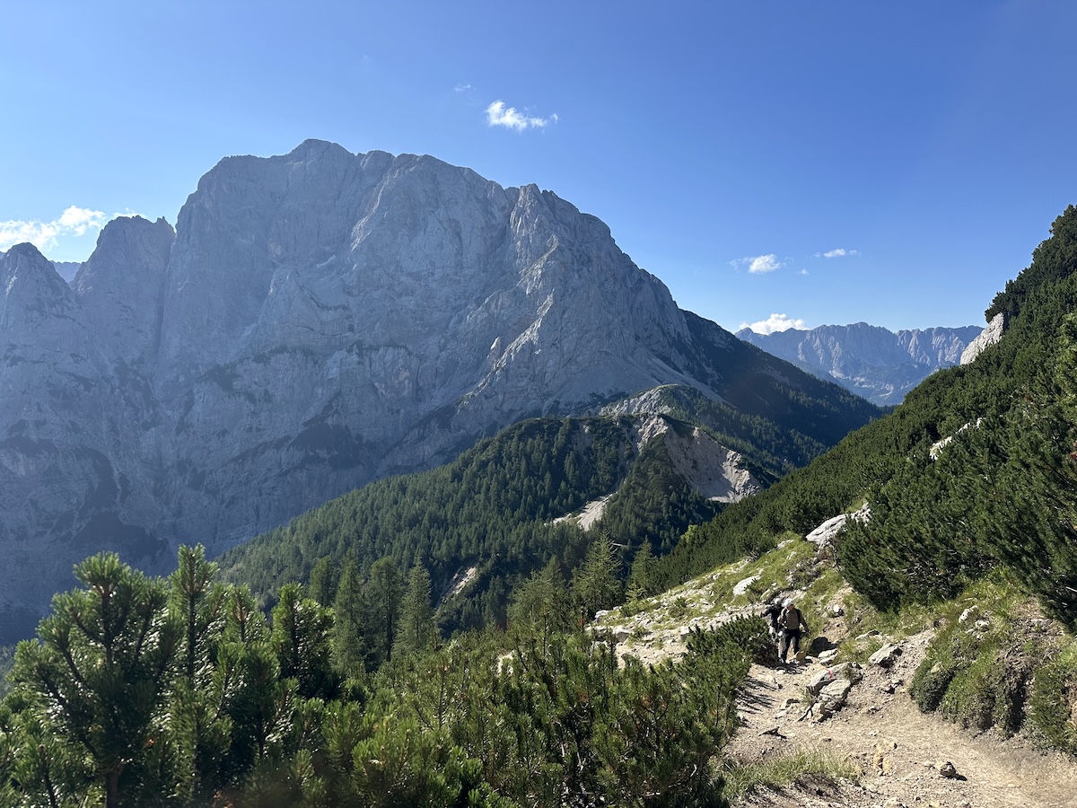 slemenova-spica-trail-above-vrsic-pass A hiker climbing the trail above Vršič Pass with Prisojnik rising across the valley.